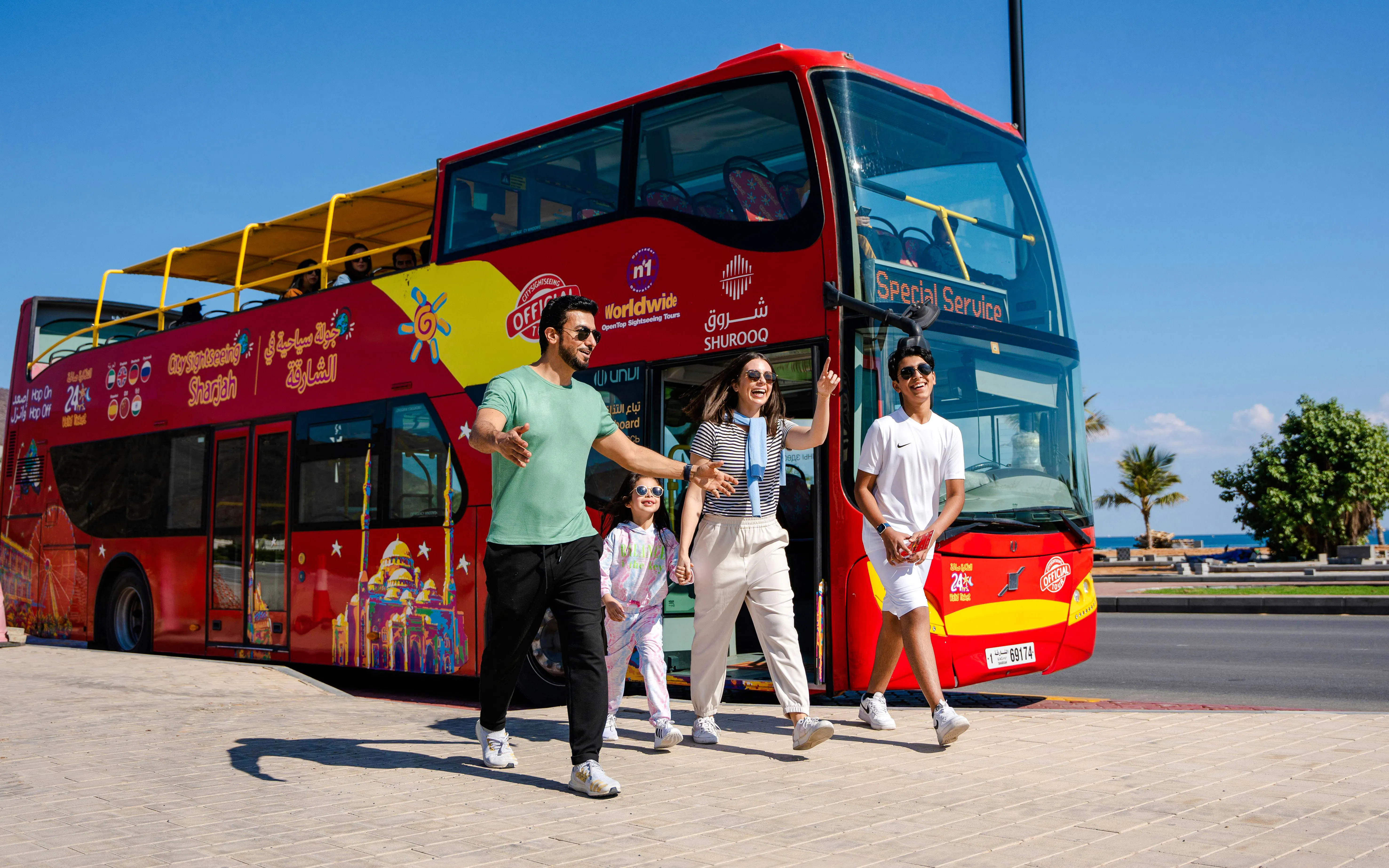 Family exiting HOHO City Sightseeing Bus in Sharjah, enjoying a sunny day tour.
