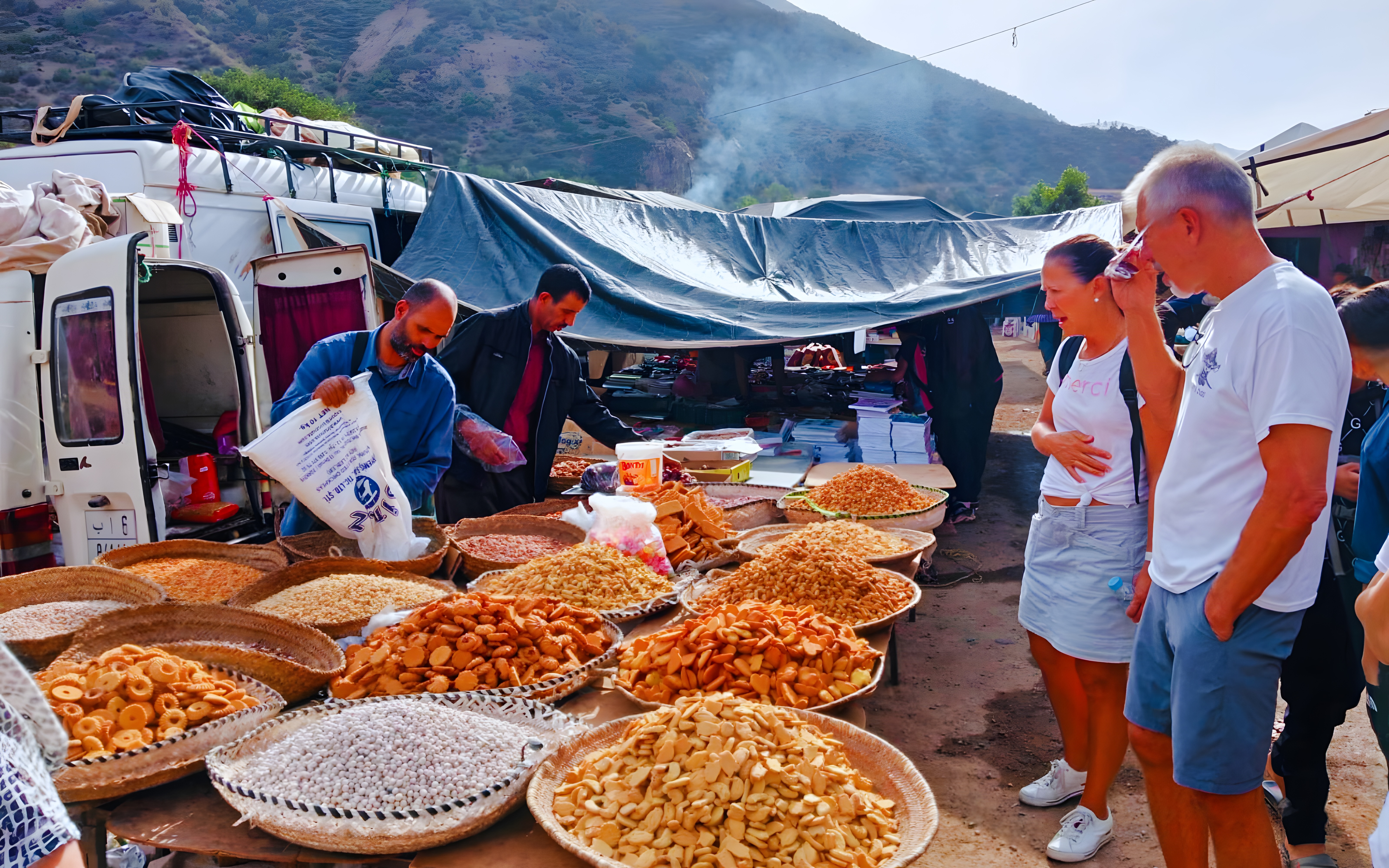 Market stall with local snacks in Ourika Valley, Morocco, with tourists browsing.