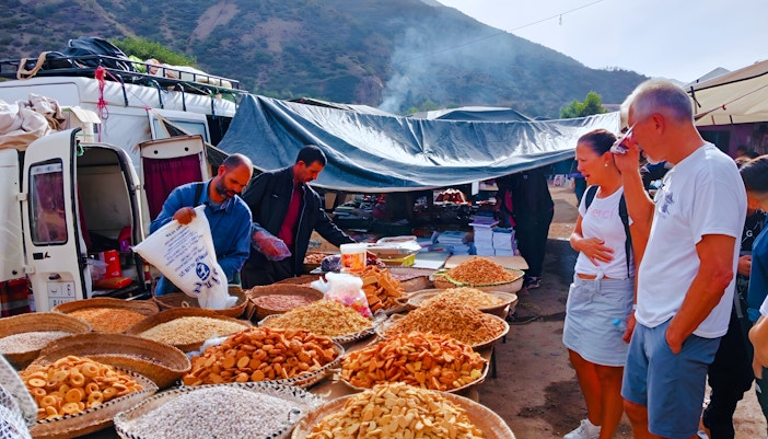 Market stall with local snacks in Ourika Valley, Morocco, with tourists browsing.