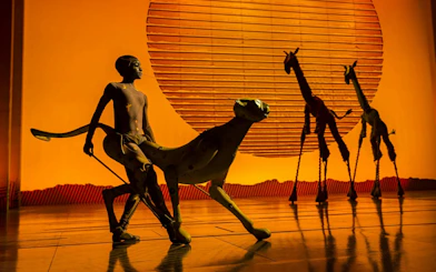 Lion King performance with actors in animal costumes on West End stage.