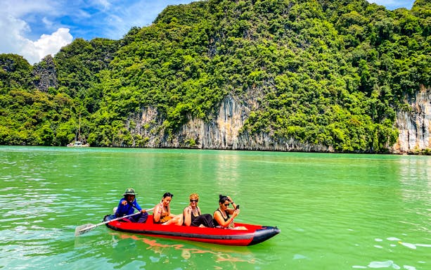 Tourists kayaking near limestone cliffs at Phang Nga Bay, with views of James Bond Island and Hong Island.
