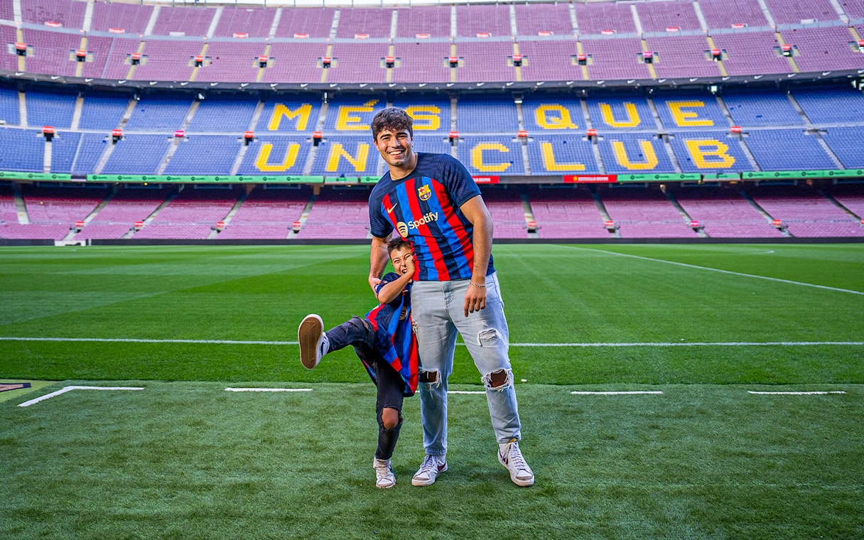 Father and child in FC Barcelona jerseys on Camp Nou field, Barcelona.