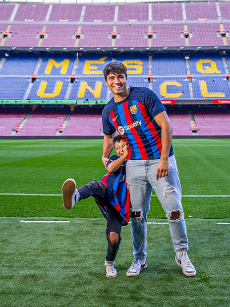 Father and child in FC Barcelona jerseys on Camp Nou field, Barcelona.