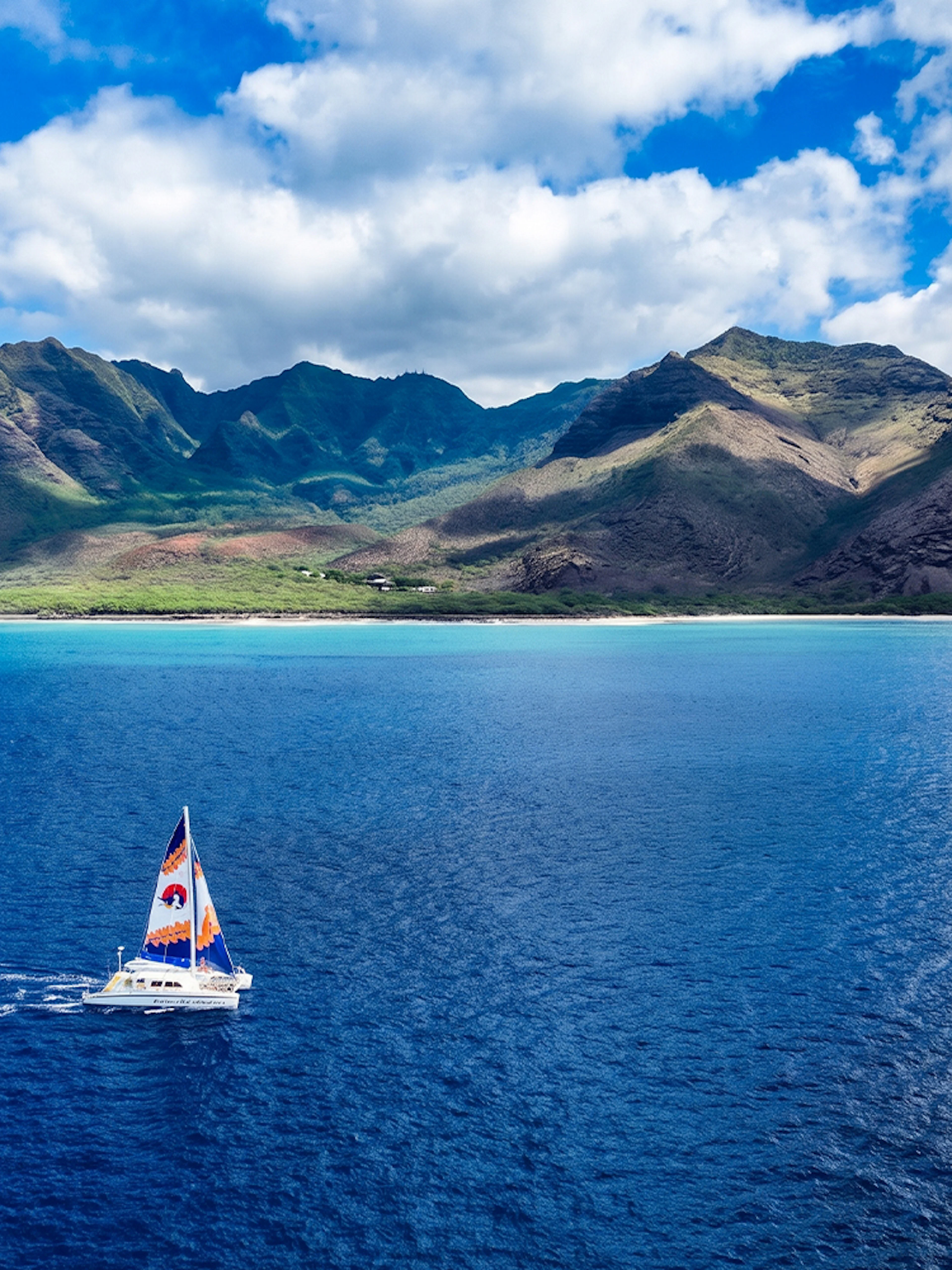 Sailboat on West Oahu waters with mountain backdrop.