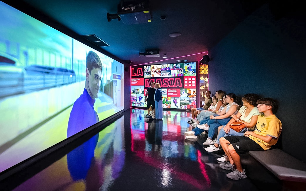 Visitors watching a video at La Masia exhibit in Spotify Camp Nou Barça Museum.