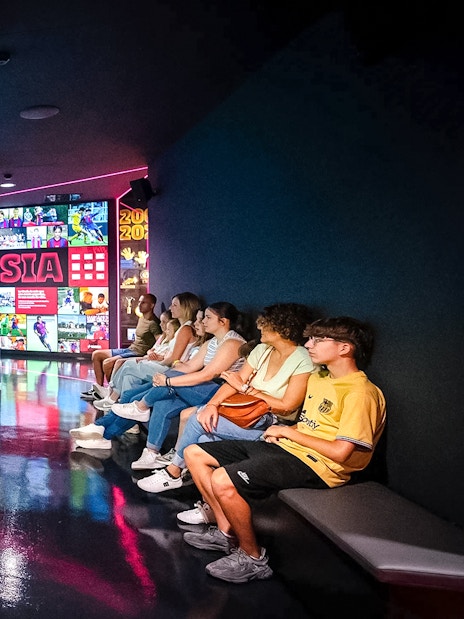 Visitors watching a video at La Masia exhibit in Spotify Camp Nou Barça Museum.