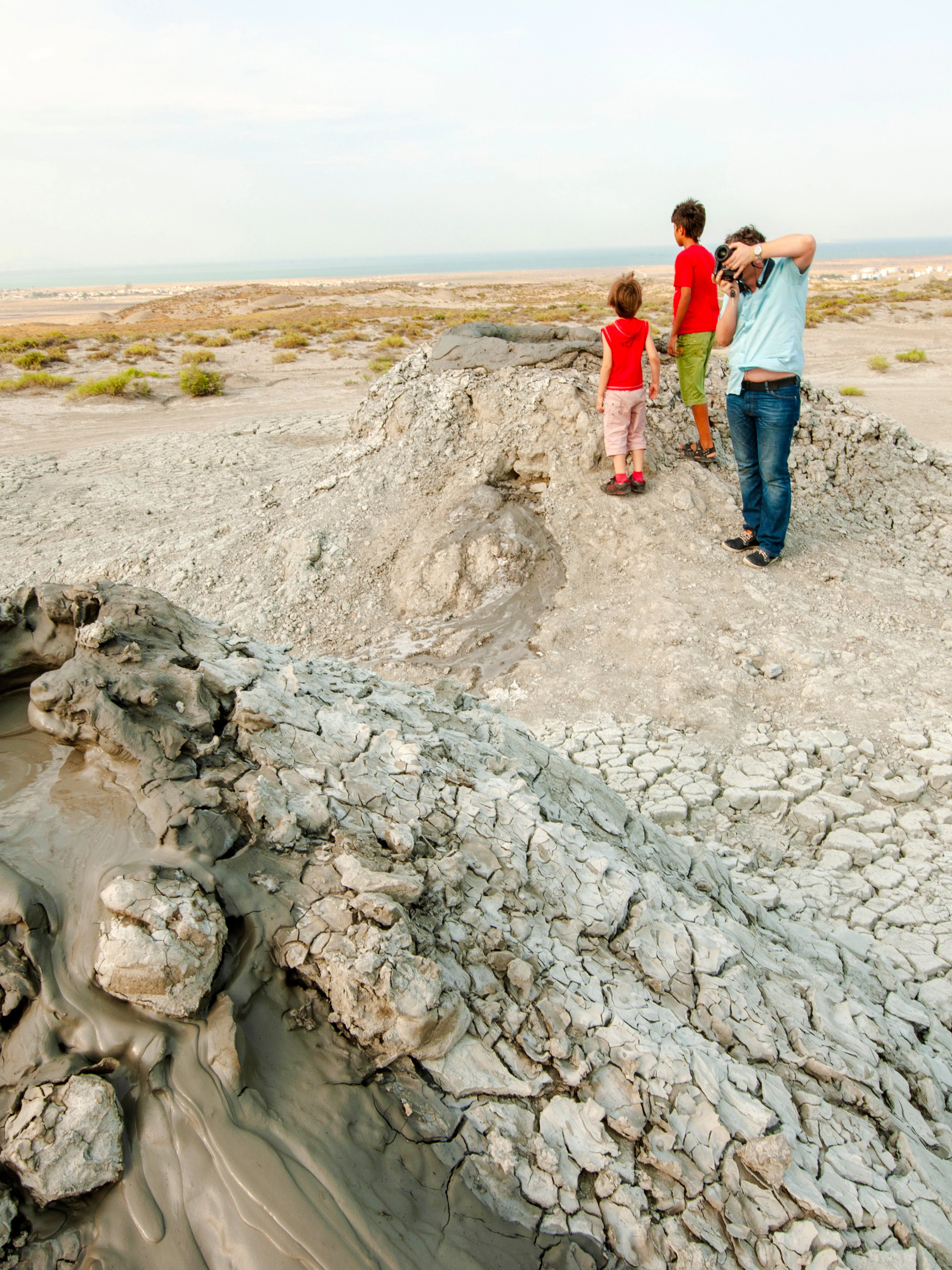 Mud volcanoes in Gobustan Reserve, Azerbaijan, with visitors observing the landscape.