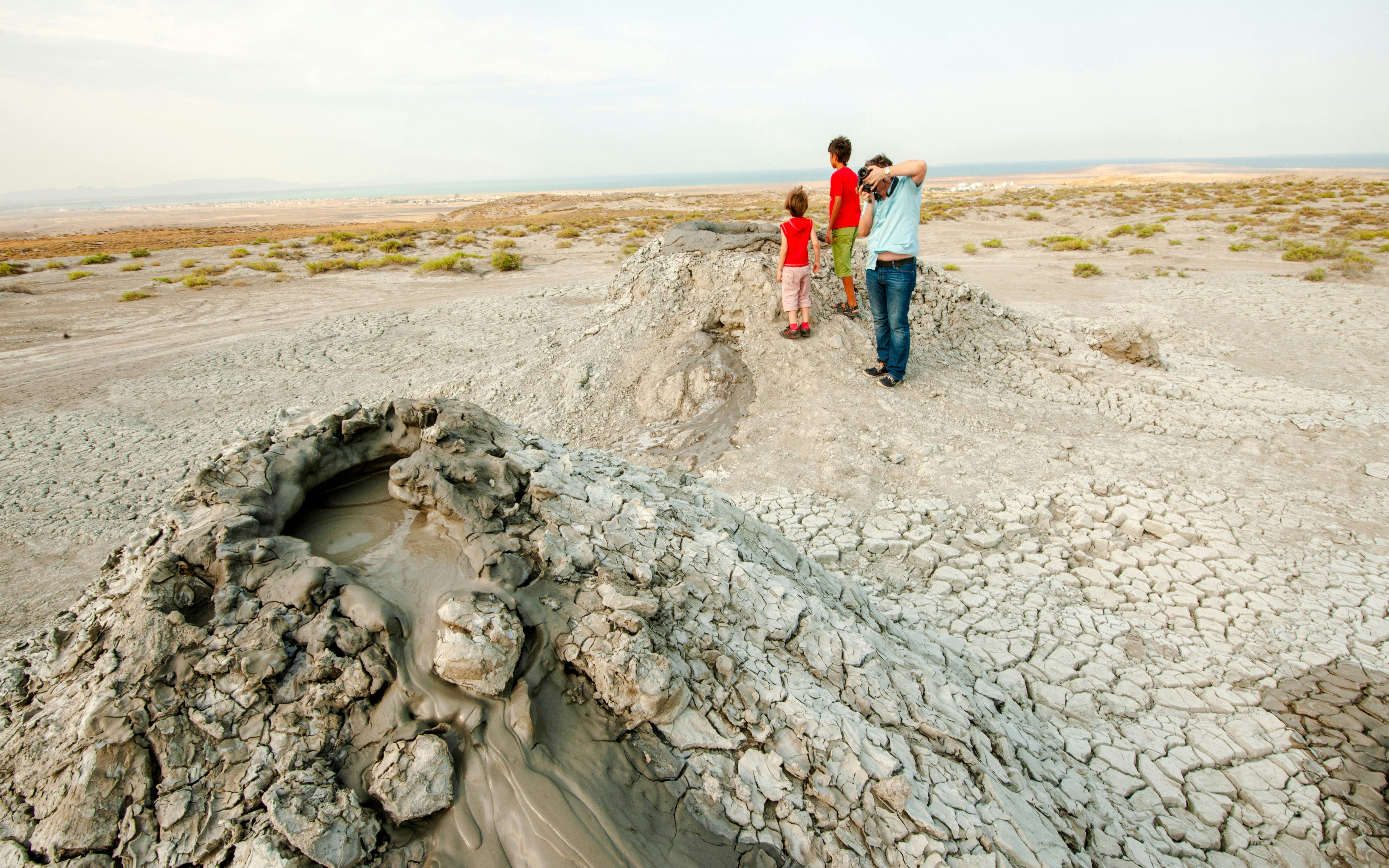Mud volcanoes in Gobustan Reserve, Azerbaijan, with visitors observing the landscape.