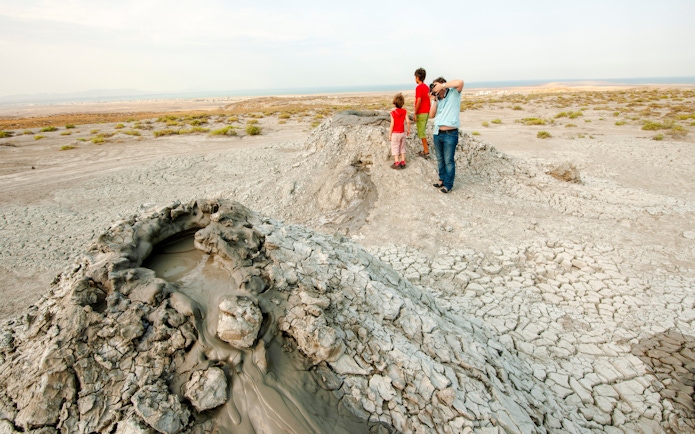 Mud volcanoes in Gobustan Reserve, Azerbaijan, with visitors observing the landscape.