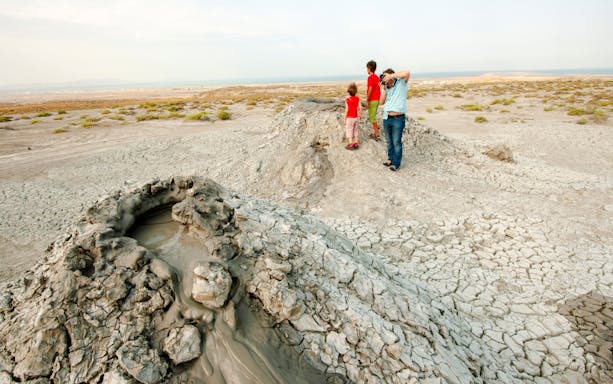 Mud volcanoes in Gobustan Reserve, Azerbaijan, with visitors observing the landscape.
