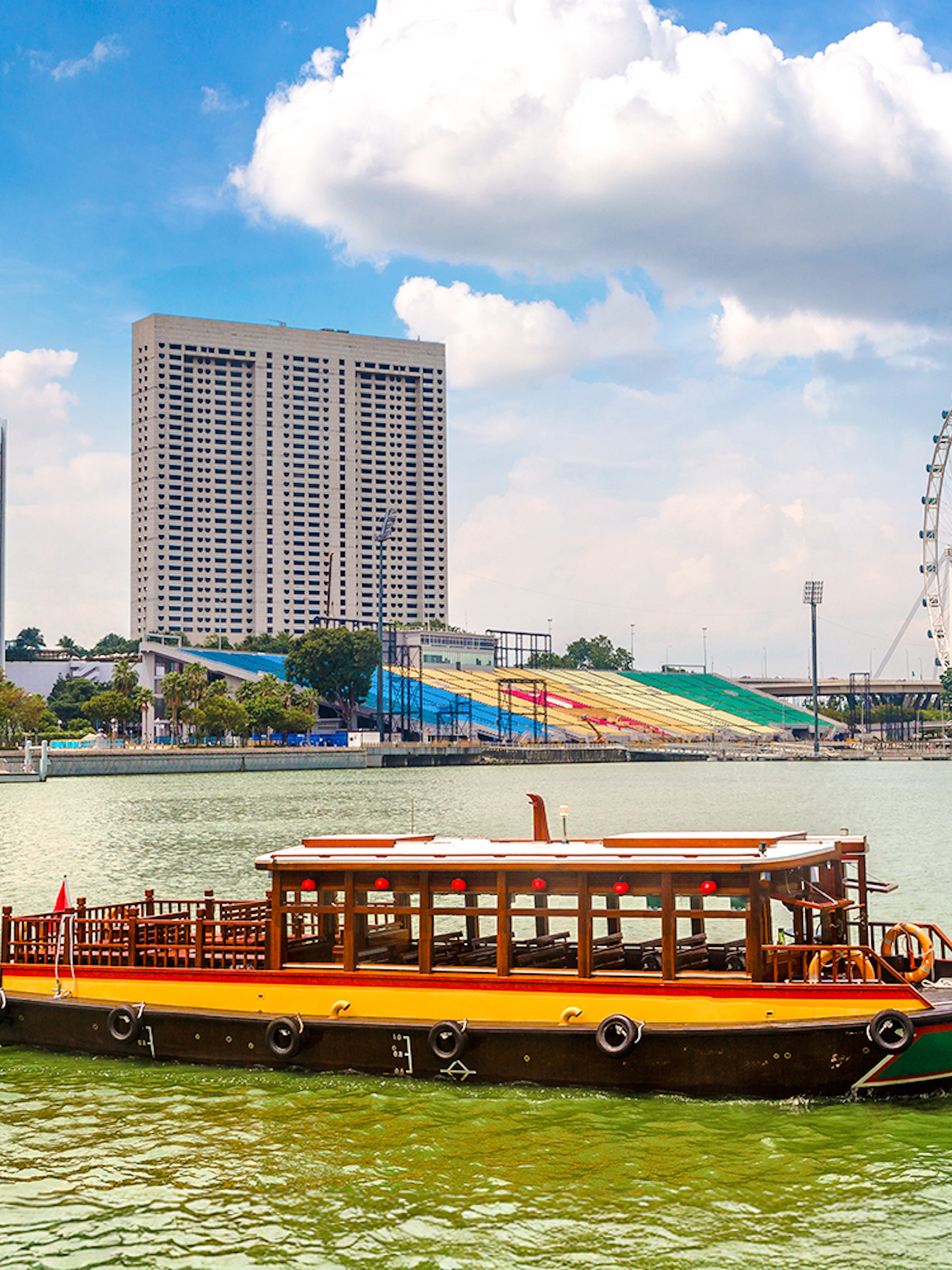 Boat on Singapore River with city skyline and Singapore Flyer in the background.