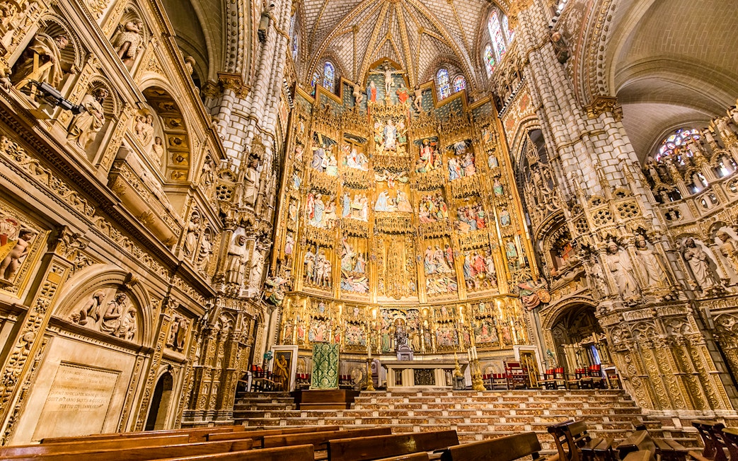 Interior of the Cathedral of Toledo showcasing ornate altarpiece and detailed stone carvings.