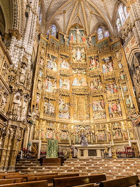 Interior of the Cathedral of Toledo showcasing ornate altarpiece and detailed stone carvings.