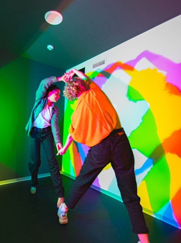 Visitors interacting with colorful light shadows at Paradox Museum.