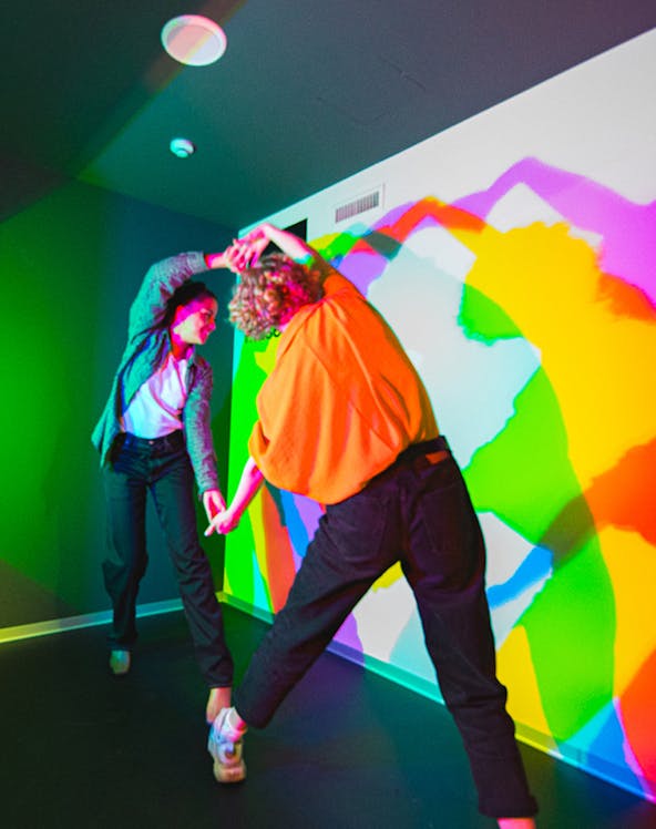 Visitors interacting with colorful light shadows at Paradox Museum.