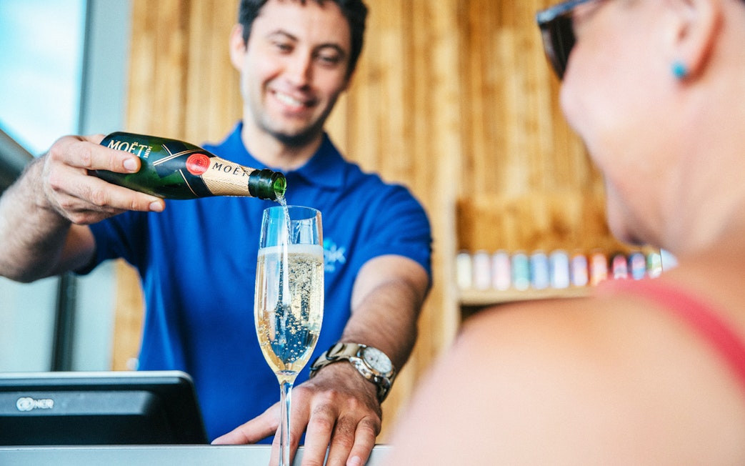 Server pouring champagne at Vök Baths bar in Egilsstaðir.