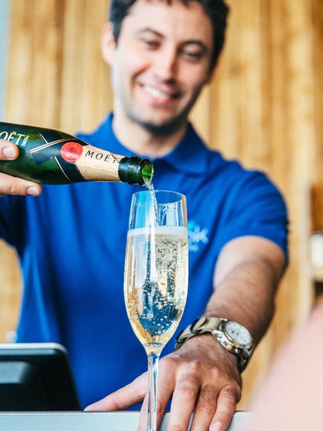 Server pouring champagne at Vök Baths bar in Egilsstaðir.