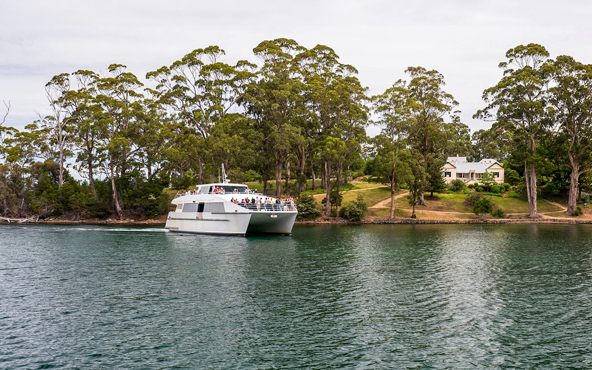 Harbour cruise near Port Arthur Historic Site with boat and lush shoreline.