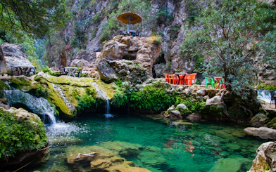 Akchour Waterfalls with seating area by clear turquoise water, Chefchaouen.