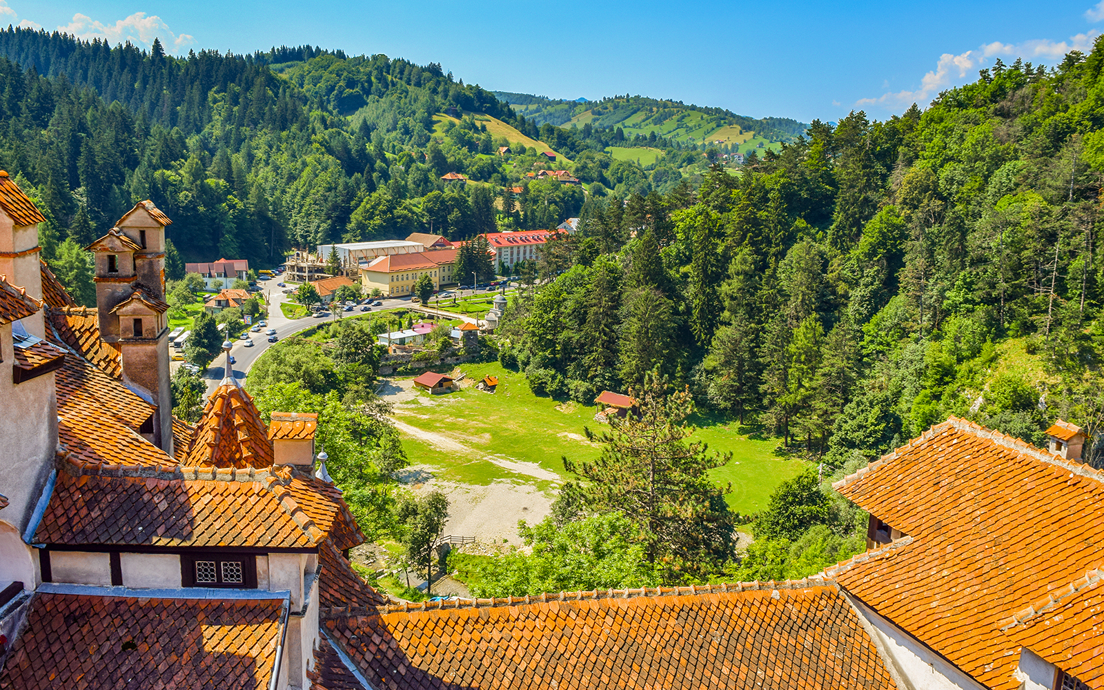 Bran Castle view of Romania cityscape with forested hills and village.