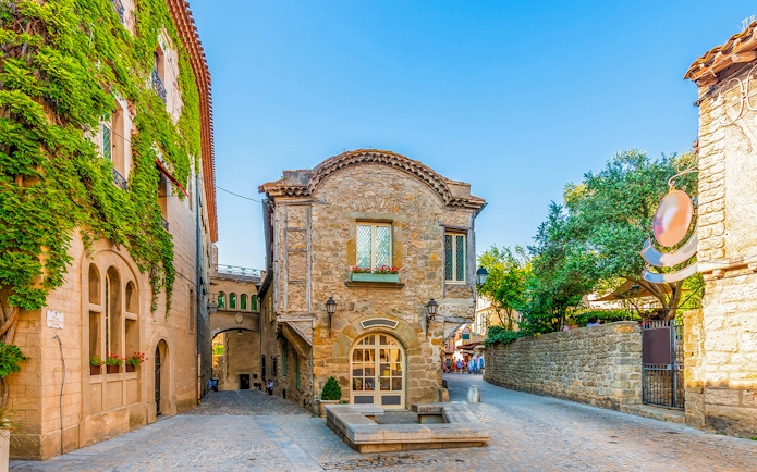 Historic stone building in Cité de Carcassonne, France, with ivy-covered walls and cobblestone street.