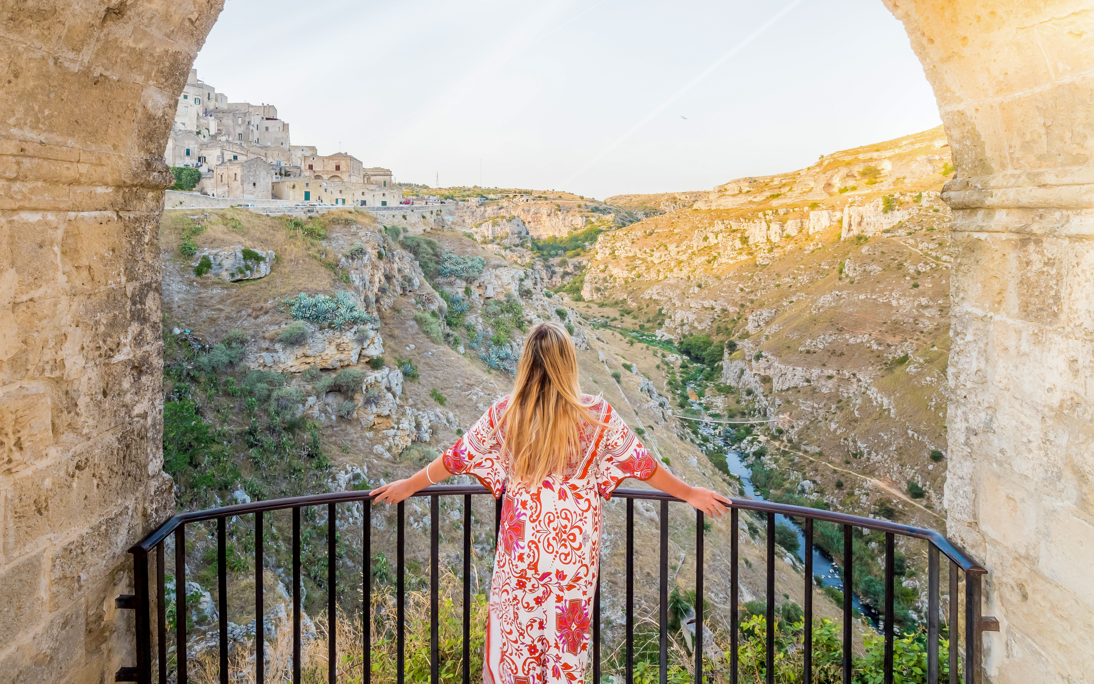 Girl overlooking the Sassi di Matera landscape from a stone arch viewpoint.