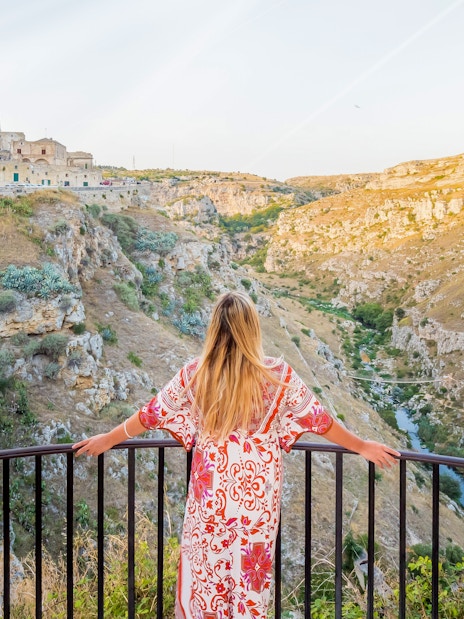 Girl overlooking the Sassi di Matera landscape from a stone arch viewpoint.