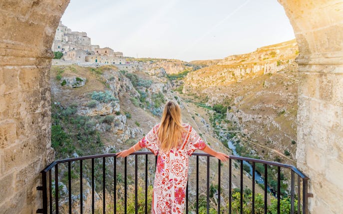 Girl overlooking the Sassi di Matera landscape from a stone arch viewpoint.