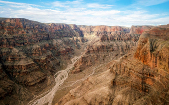 West Rim of the Grand Canyon with layered rock formations and a winding river below.