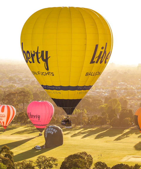 Hot air balloons floating over Melbourne at sunrise.