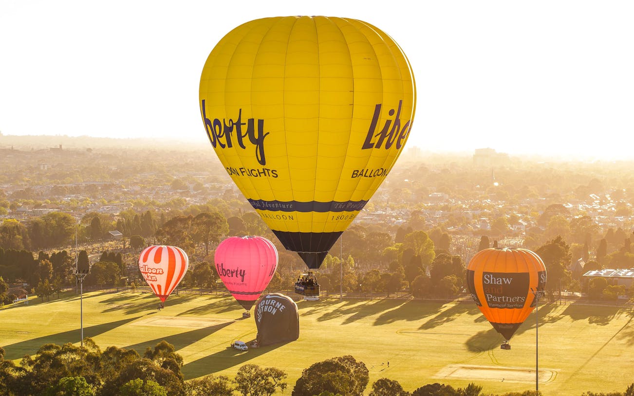 Hot air balloons floating over Melbourne at sunrise.