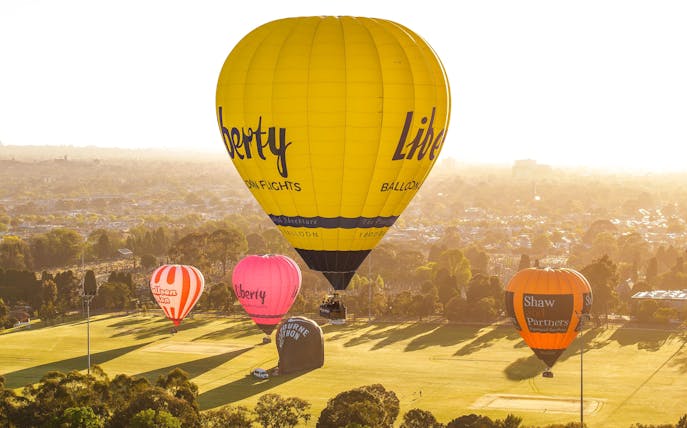 Hot air balloons floating over Melbourne at sunrise.