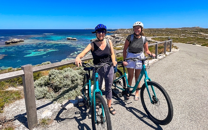 Cyclists on Rottnest Island with ocean view, accessible via ferry from Perth or Fremantle.