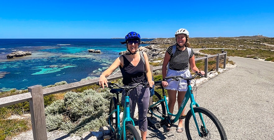 Cyclists on Rottnest Island with ocean view, accessible via ferry from Perth or Fremantle.