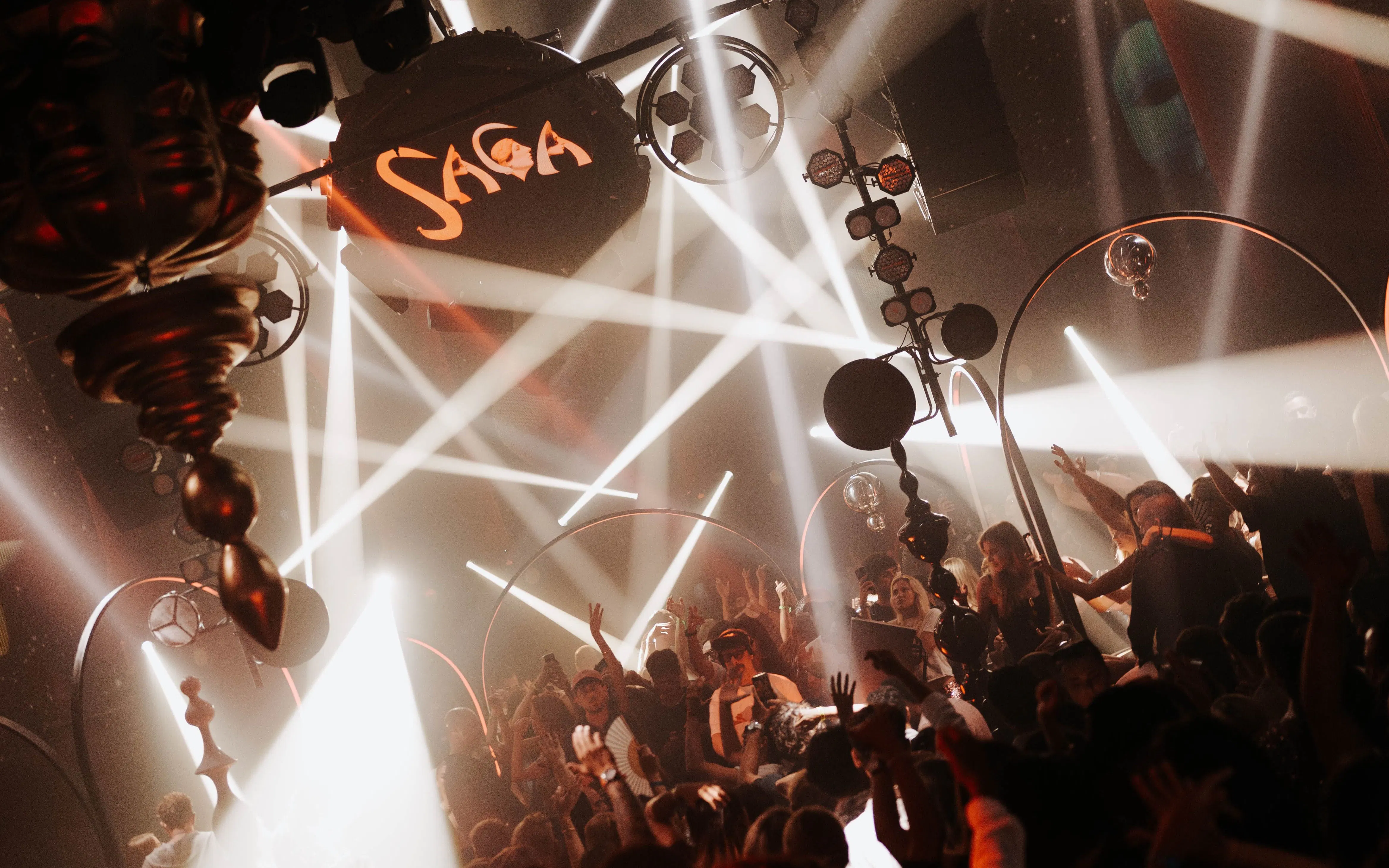 DJ performing at Club Chinois during SAGA event, Ibiza, with vibrant crowd and lights.