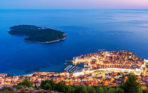 Aerial view of Dubrovnik's old town and Lokrum Island at sunset.