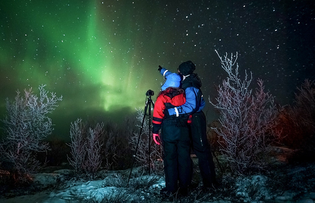 Tour guide with camera gear capturing northern lights in Tromsø, Norway.