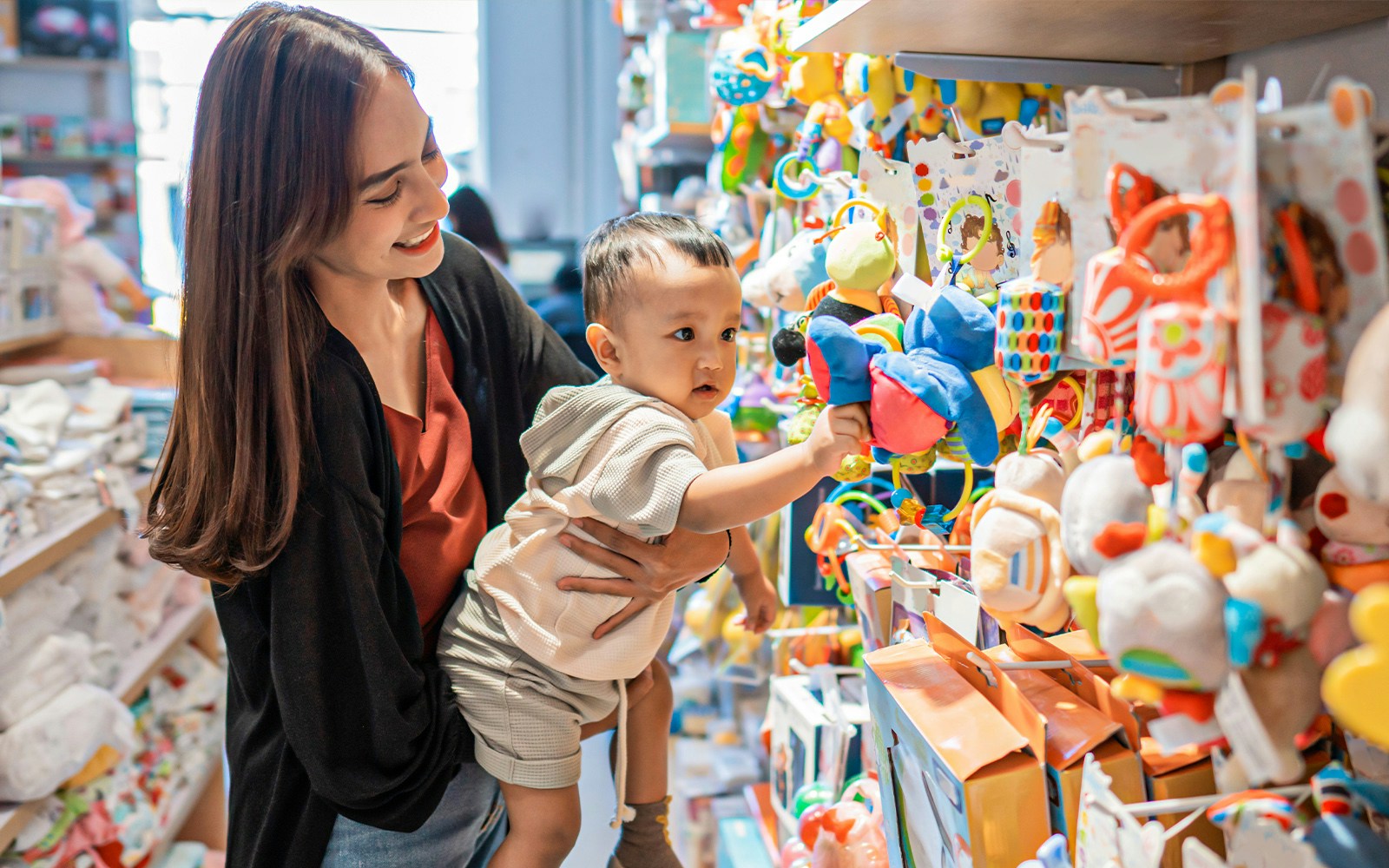 Mother and child exploring colorful toys at Warner Bros. shopping area.