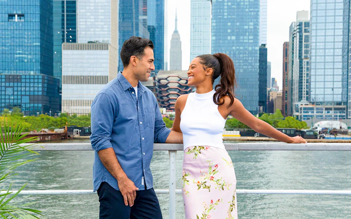 Couple enjoying New York Signature Dinner Cruise with city skyline in background.