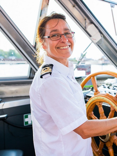 Boat captain steering on City Sightseeing Amsterdam Hop-On Hop-Off tour.