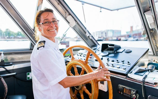 Boat captain steering on City Sightseeing Amsterdam Hop-On Hop-Off tour.