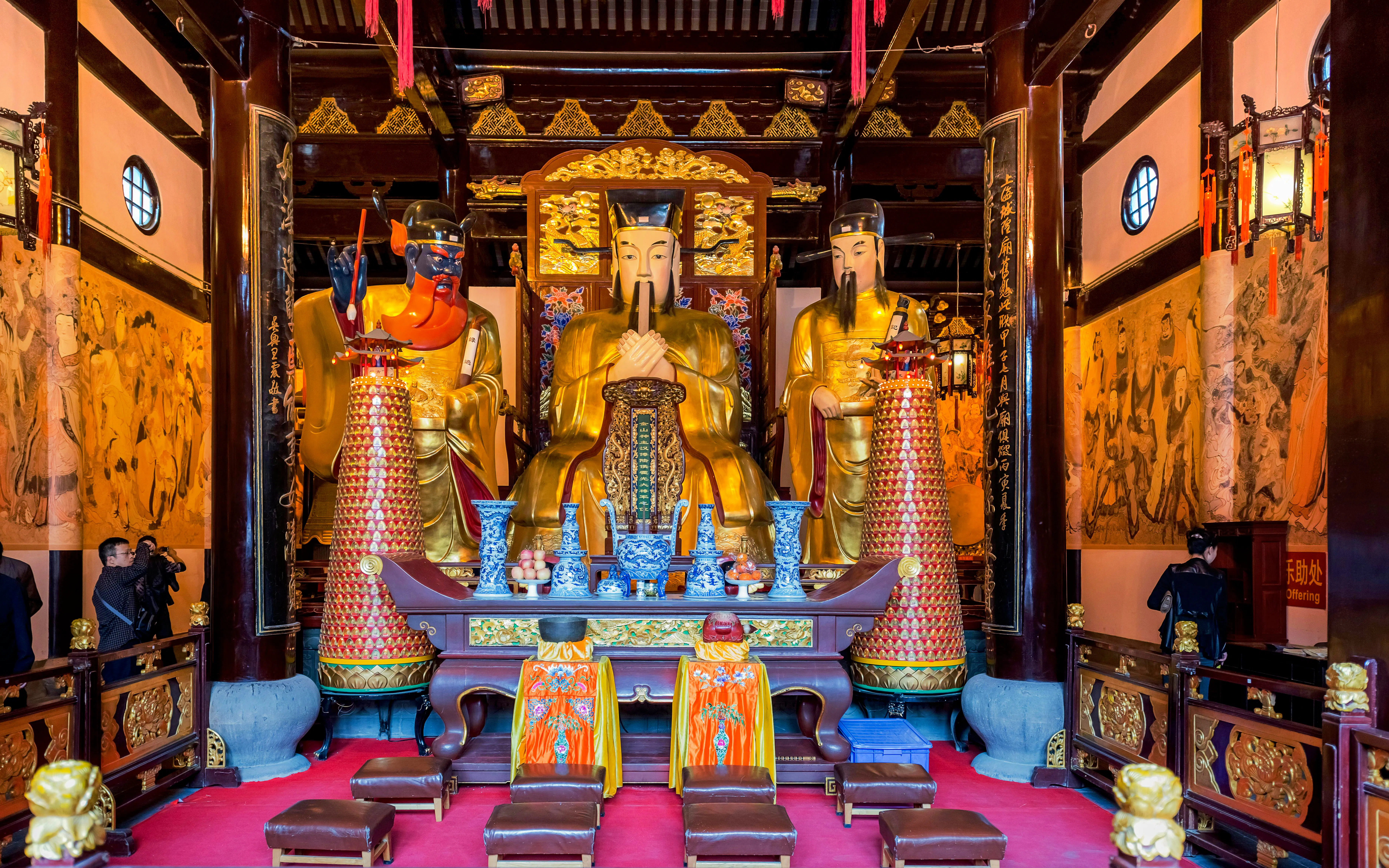 Interior of City God Temple of Shanghai with golden Taoist deity statues.
