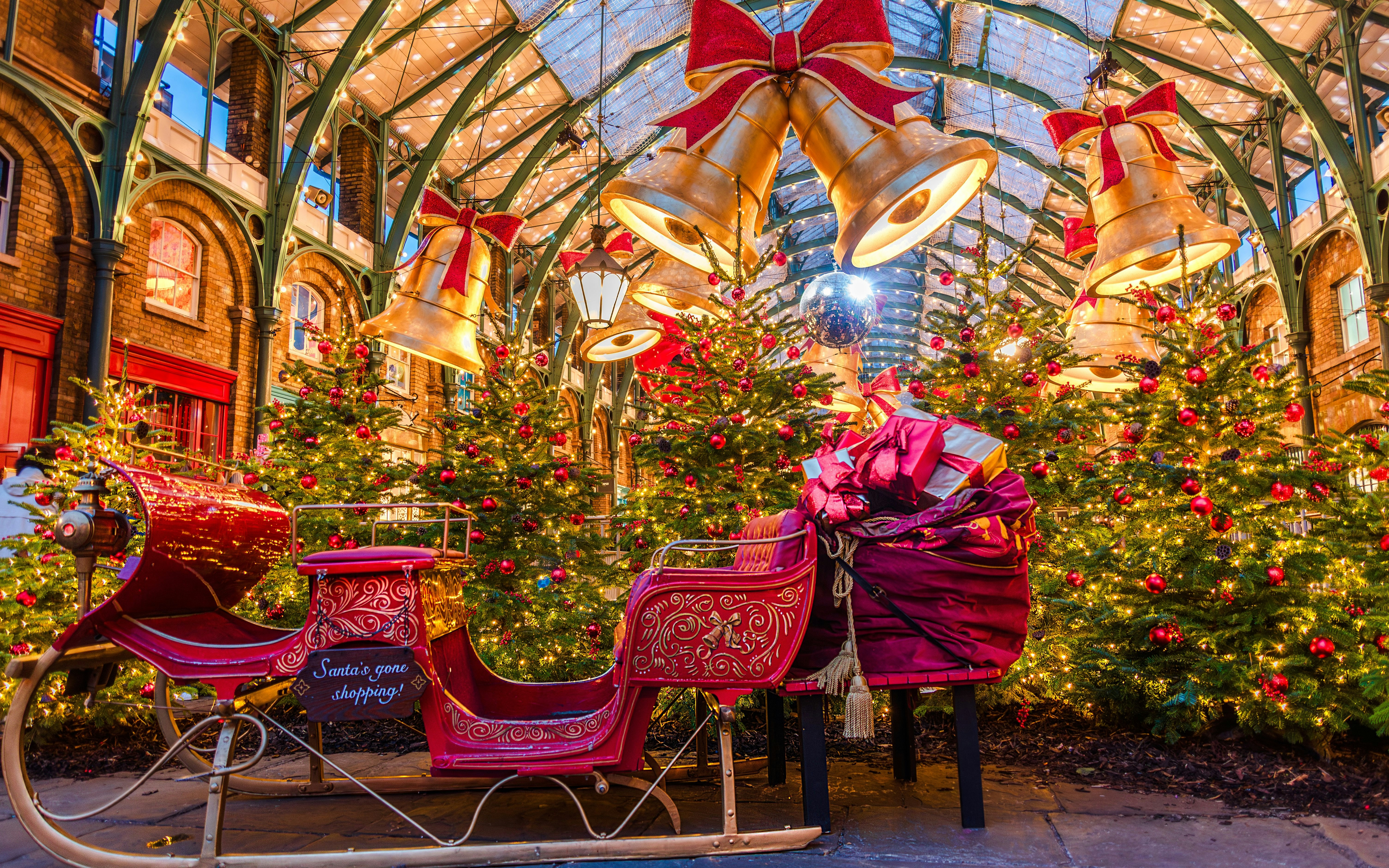 Covent Garden Christmas scene with decorated trees, large bells, and a festive sleigh.