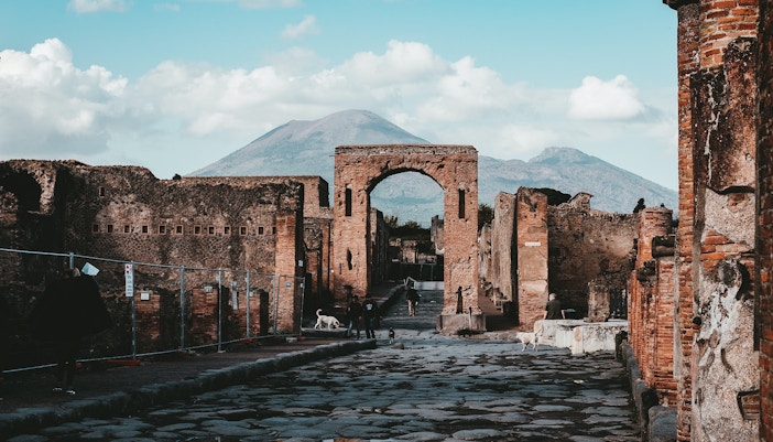 Ancient ruins and archway with Mount Vesuvius in the background at Pompeii Archaeological Park.