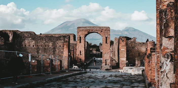 Ancient ruins and archway with Mount Vesuvius in the background at Pompeii Archaeological Park.