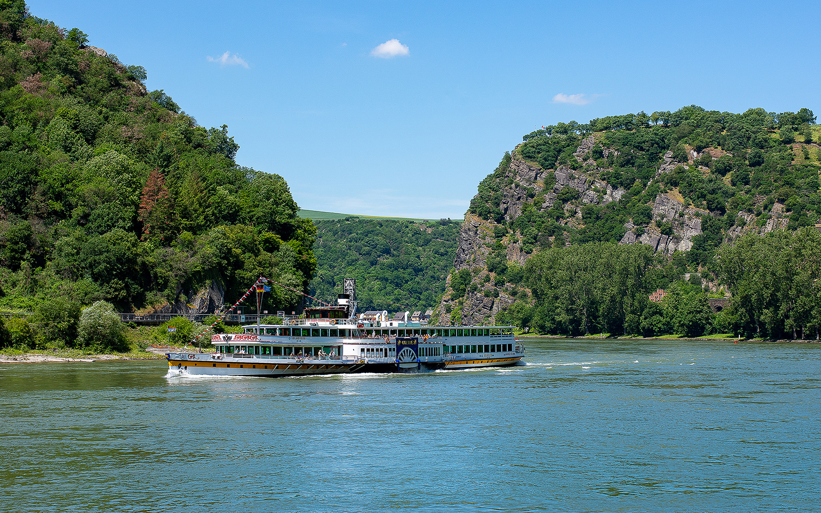 Paddle steamer Goethe cruising on the Rhine River with lush hills in the background.