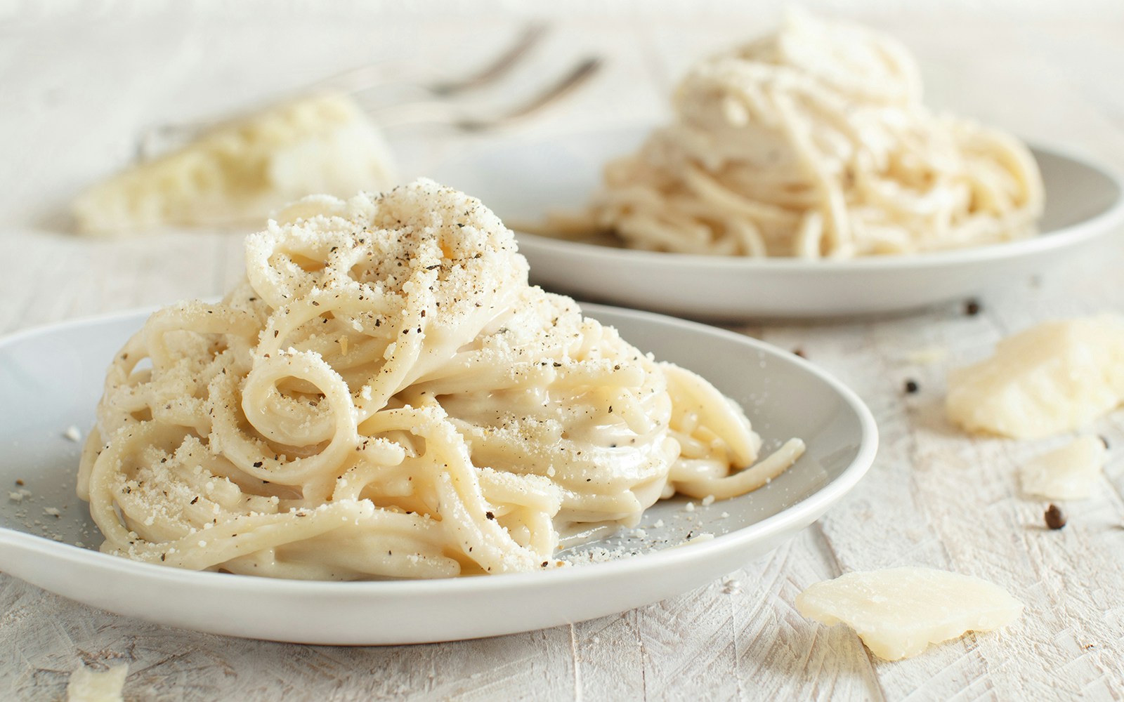 Cacio e pepe spaghetti on a plate with grated cheese and pepper.