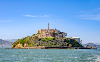 Ferry view of Alcatraz Island with historic buildings in San Francisco Bay.