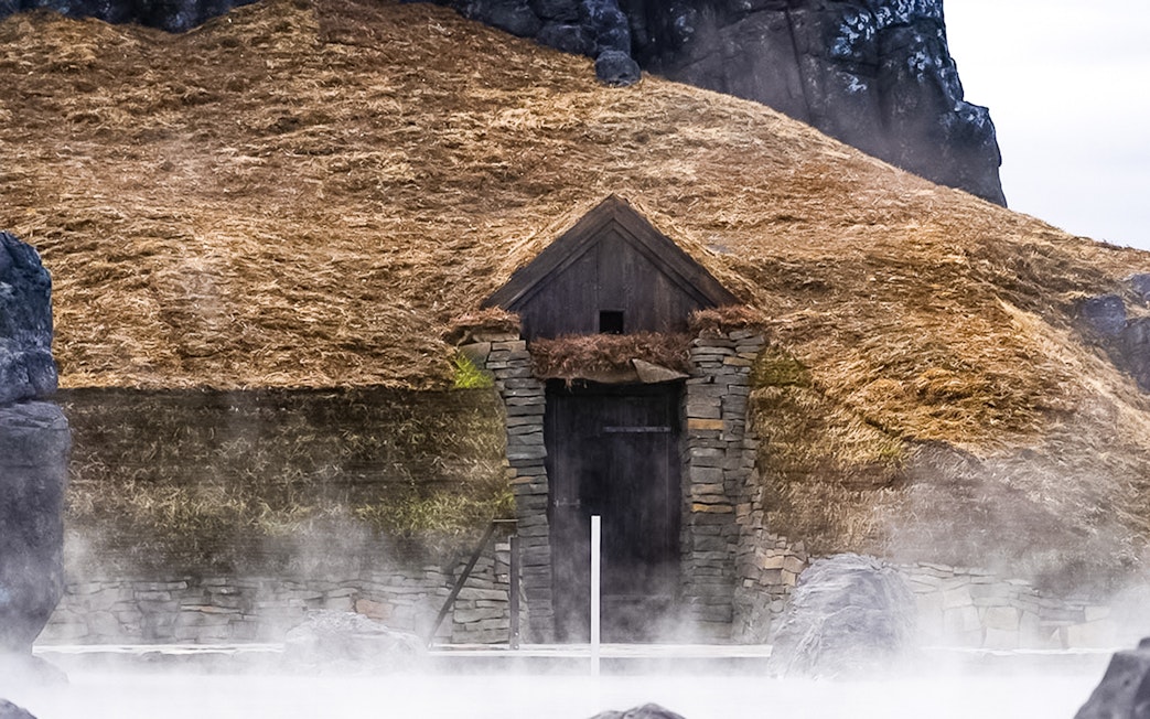 Turfhouse entrance at Sky Lagoon with mist rising from the pool.