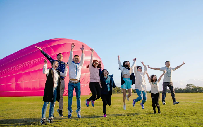 Group jumping in front of a pink hot air balloon at Sirromet Winery, Gold Coast.